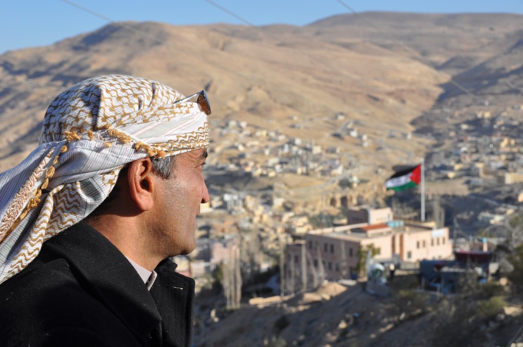 Mohammed looking over Petra town and the Jordanian flag. 