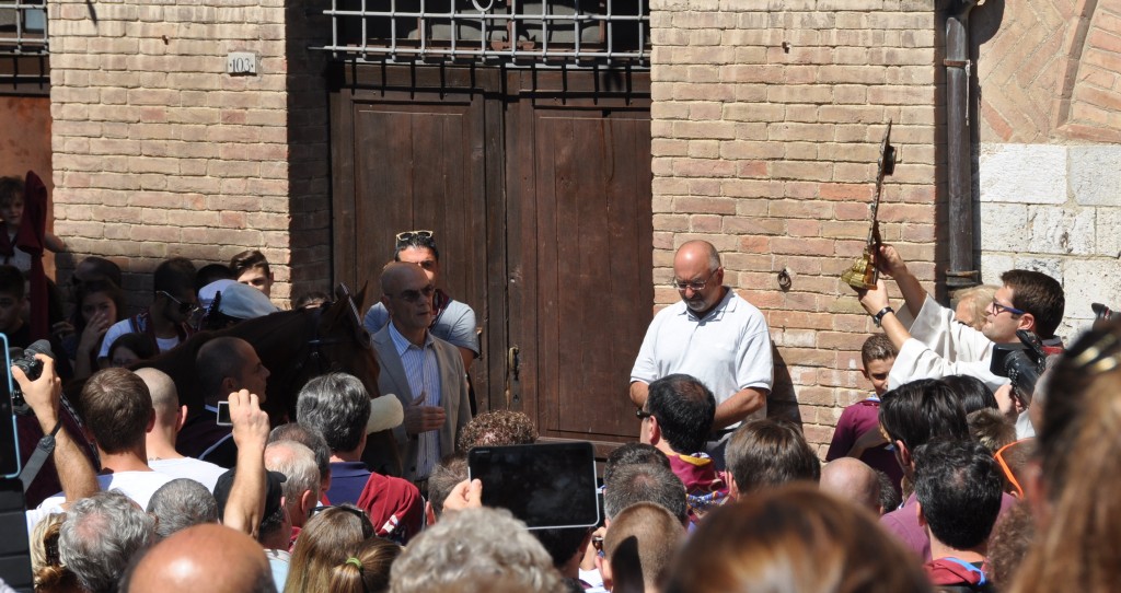 The horse is on the left and the Father is holding the cross on the right. 